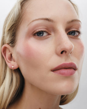 Blonde model wears Lit Up Highlight Stick in Petal.