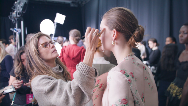 Gucci Westman doing the make up of a model backstage at fashion week in new york city