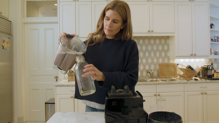 Gucci pours strawberry hemp milk into a container in her kitchen