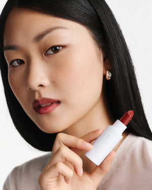 Woman holding a red lipstick with red lipstick on a white background