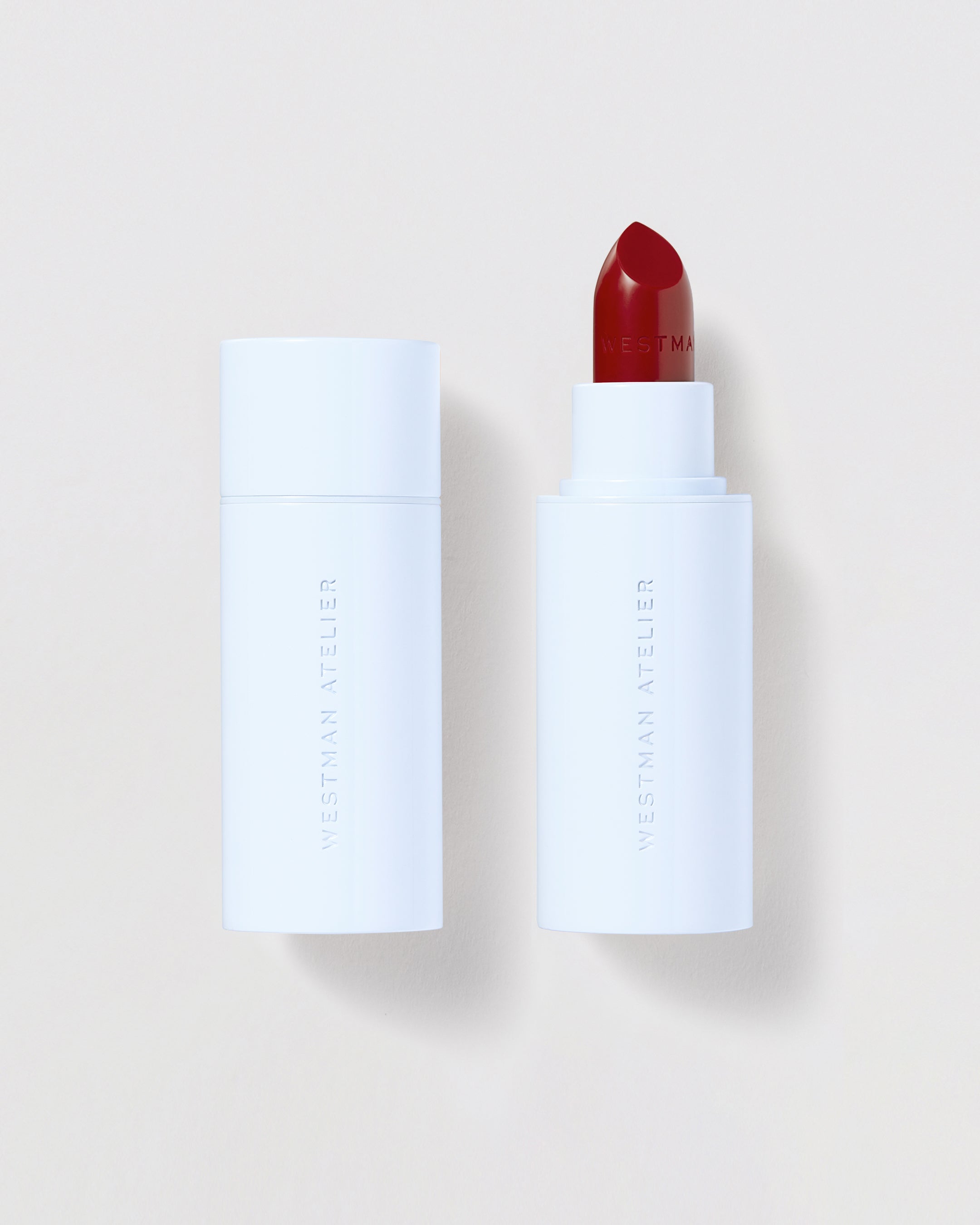 Red lipstick in a blue tube against a beige background.
