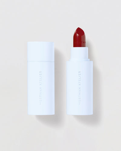 Red lipstick in a blue tube against a beige background.

