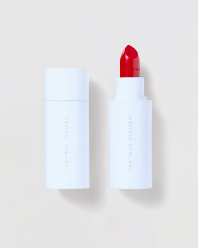 Red lipstick in a blue tube on a light beige background