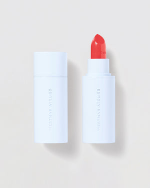 Lipstick with white casing and red cap on a light beige background