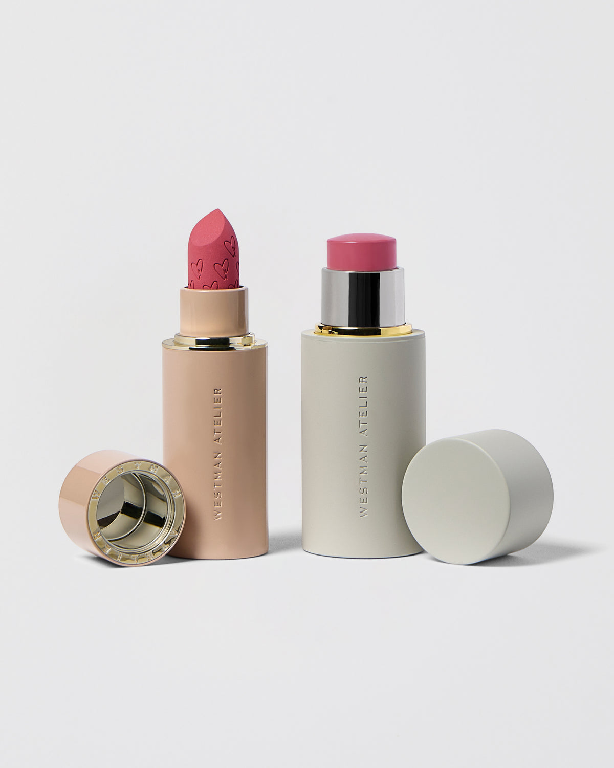 Two lipsticks with their cases on a light gray background