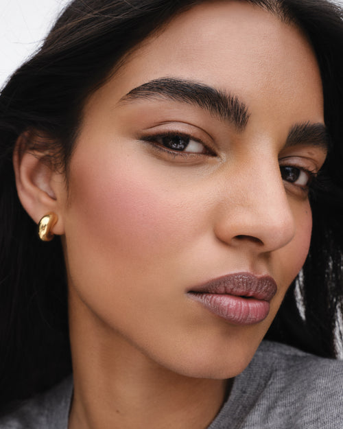 Model wears Baby Cheeks & Face Trace Sculpting Powder Duo in Tulle / Truffle. 