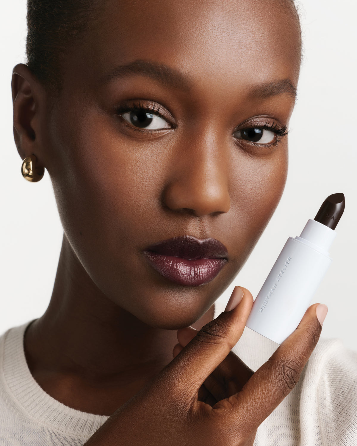 Model wears dark berry lipstick.