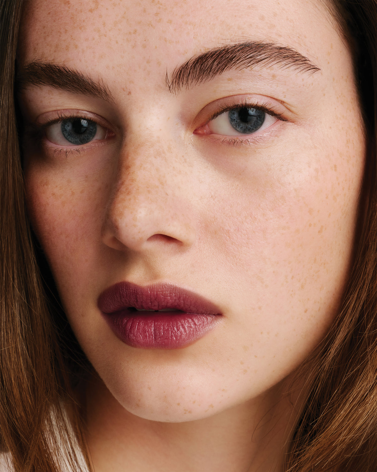 Model wears dark berry lipstick.