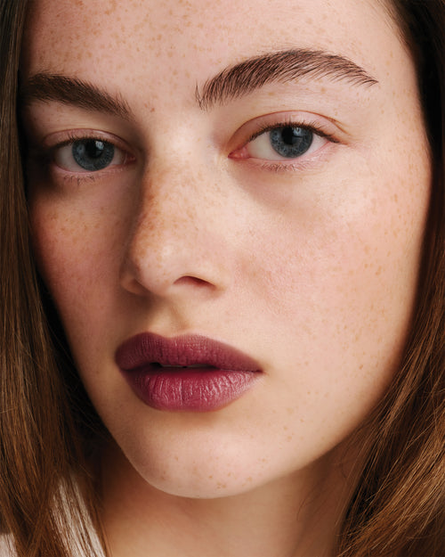 Model wears dark berry lipstick.