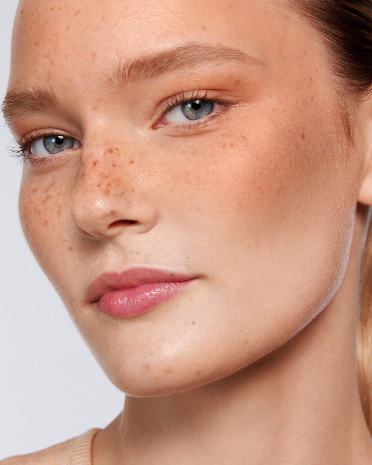 Blonde model with freckles wearing bronzing drops in Soleil Parfait 2.