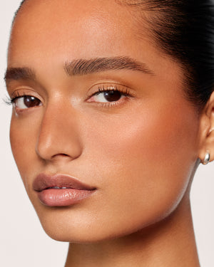 Model with medium-deep skin tone wearing Sun Tone Bronzing Drops in Soleil Parfait 3.