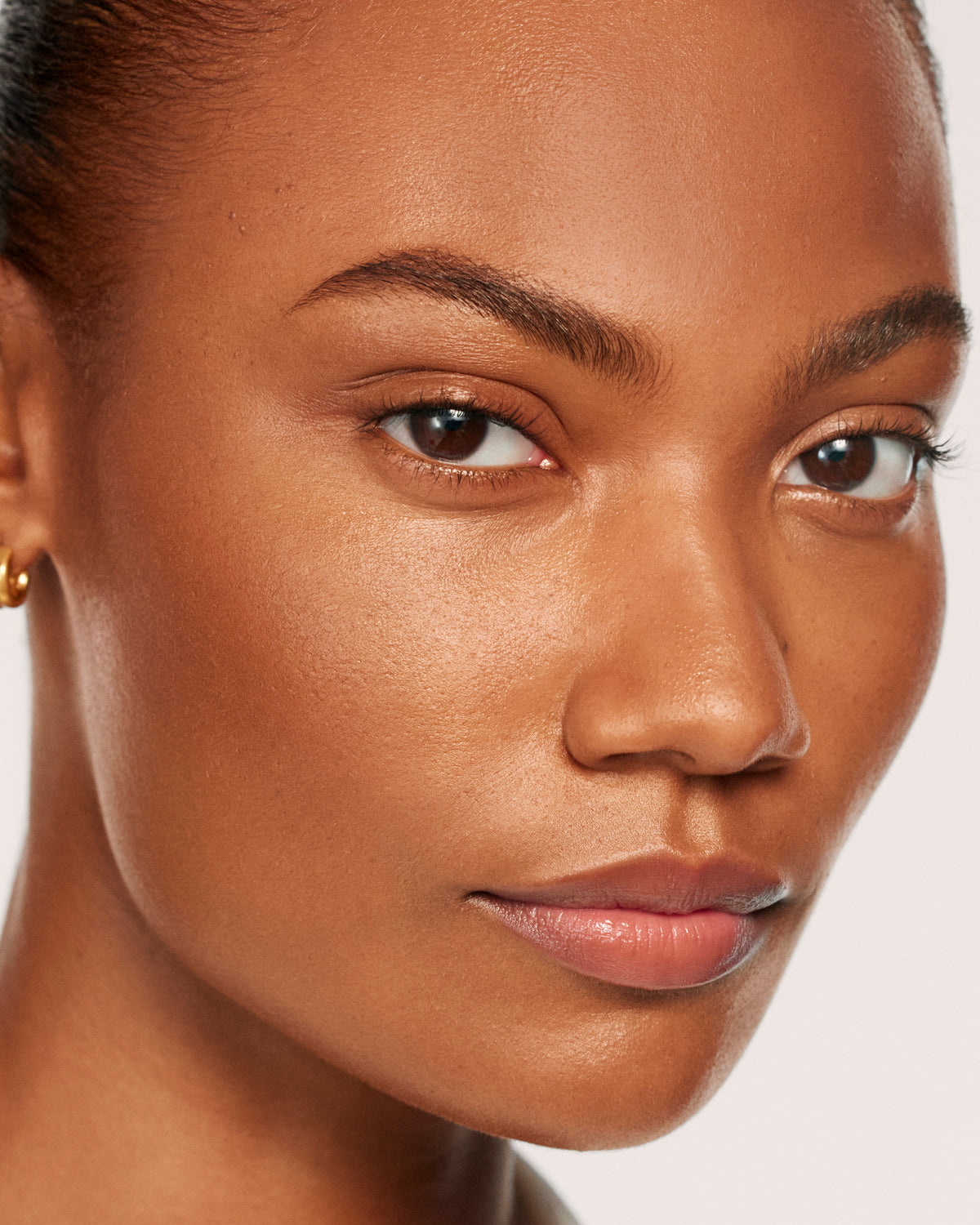 Model with deep skin tone wearing Sun Tone Bronzing Drops in Soleil Parfait 4.