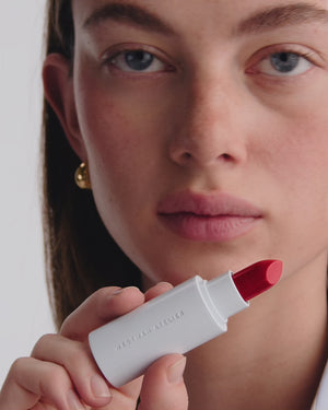 Model applies red lipstick.