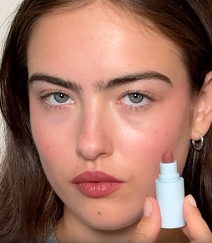 Brunette model applies three lipsticks.