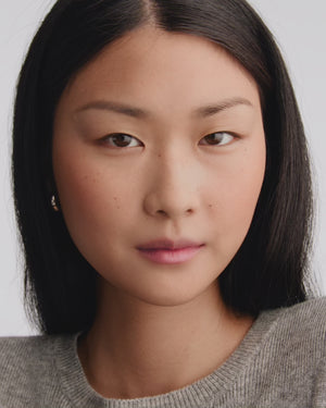 Model applies coral lipstick.
