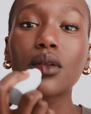 Model applies red lipstick.