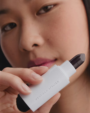 Model applies dark berry lipstick.